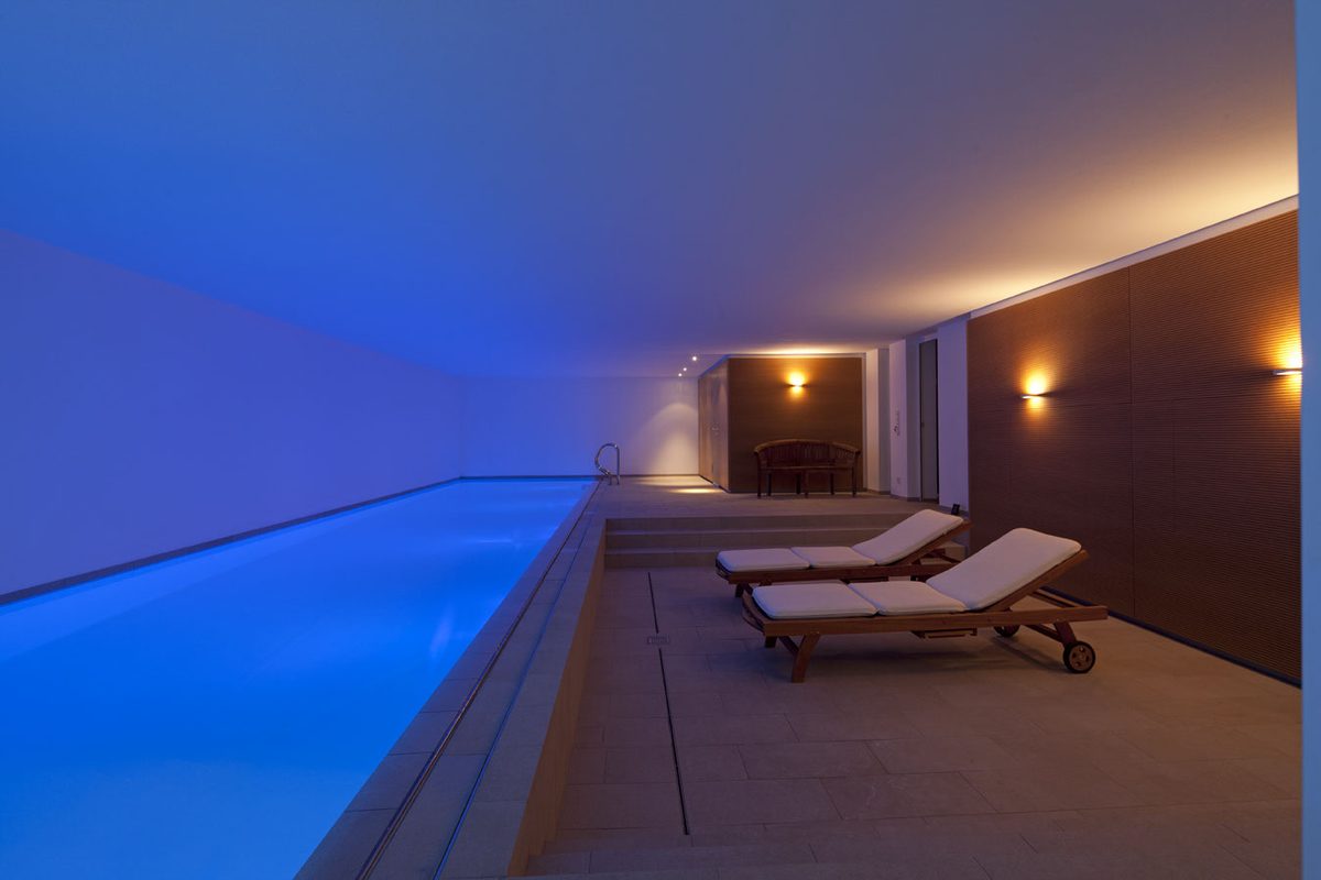 Schwimmbad mit blauer Beleuchtung und Liegen